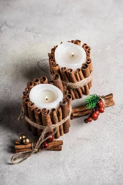 Handmade candles wrapped with cinnamon sticks and twine on a textured background