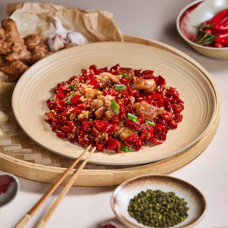 Plate of Sichuanese spicy wok-fried chicken with dried chilies and green peppercorns