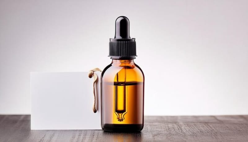 Amber glass dropper bottle with essential oil on a wooden surface