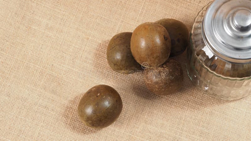 Whole dried monk fruit arranged beside a glass jar on a linen cloth