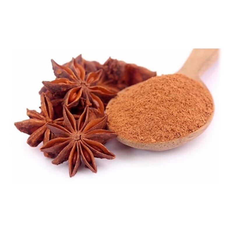 Whole star anise pods beside a wooden spoon of ground star anise on white